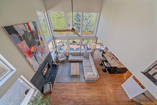 10127 W 100th Ct, Westminster, CO 80021 - living room featuring a towering ceiling, wood finished floors, healthy amount of natural light, and a tiled fireplace