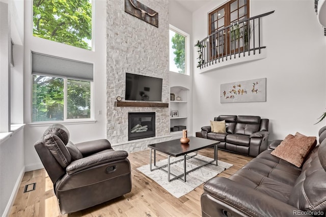 1588 W 111th Ave, Northglenn, CO 80234 - living room with healthy amount of natural light, a towering ceiling, a fireplace, wood finished floors, and built in features