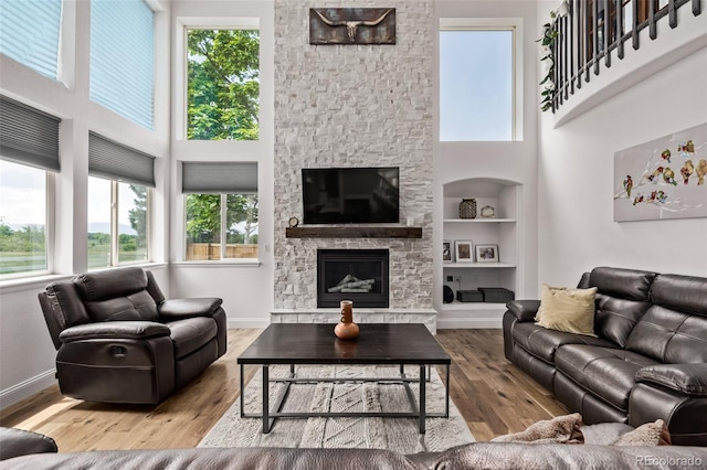 1588 W 111th Ave, Northglenn, CO 80234 - living room featuring built in shelves, a high ceiling, wood finished floors, and a stone fireplace