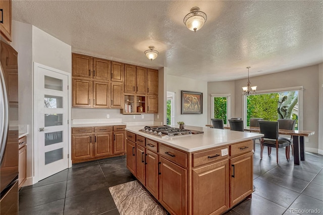 1915 Hunters Point Ln, Colorado Springs, CO 80919 - kitchen with appliances with stainless steel finishes, brown cabinets, light countertops, a chandelier, and a center island