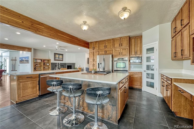 1915 Hunters Point Ln, Colorado Springs, CO 80919 - kitchen featuring appliances with stainless steel finishes, a kitchen island, brown cabinets, beamed ceiling, and recessed lighting