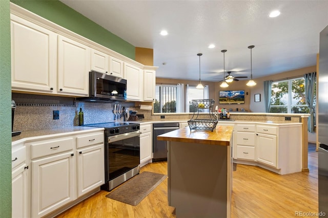 kitchen featuring stainless steel appliances, a center island, kitchen peninsula, hanging light fixtures, and butcher block countertops