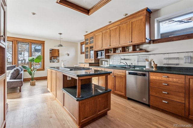 kitchen with a kitchen island, appliances with stainless steel finishes, decorative light fixtures, sink, and light hardwood / wood-style flooring