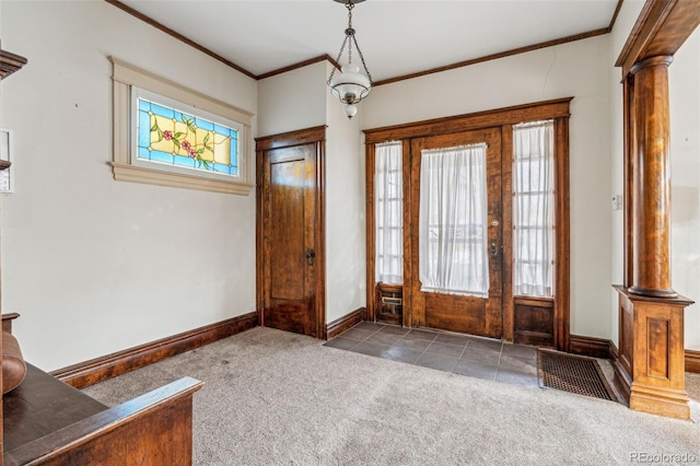 foyer with ornate columns, dark colored carpet, and ornamental molding