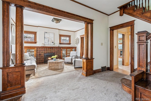 living area with decorative columns, ornamental molding, and carpet flooring