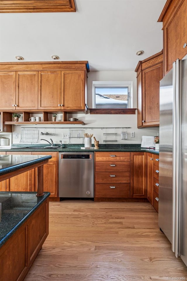 kitchen with appliances with stainless steel finishes, light hardwood / wood-style floors, and dark stone counters