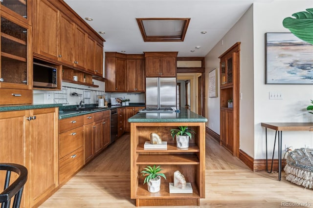 kitchen with appliances with stainless steel finishes, sink, decorative backsplash, a center island, and light hardwood / wood-style floors