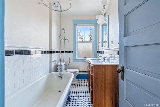 bathroom featuring toilet, tile walls, vanity, and a tub to relax in