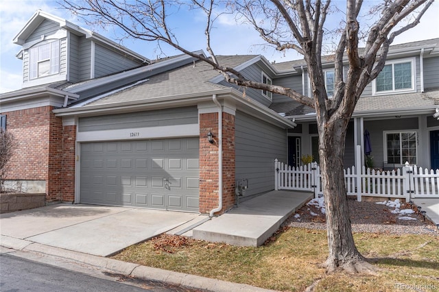 view of side of home with a garage, brick siding, a shingled roof, fence, and driveway