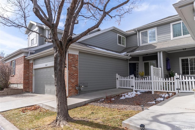 view of front of house featuring concrete driveway, brick siding, fence, and an attached garage