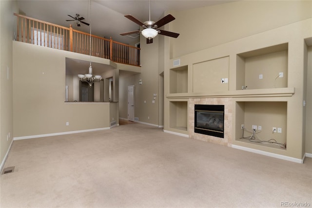 unfurnished living room featuring carpet, visible vents, built in features, and ceiling fan with notable chandelier