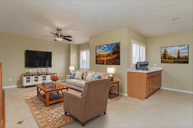 living area featuring a ceiling fan and baseboards