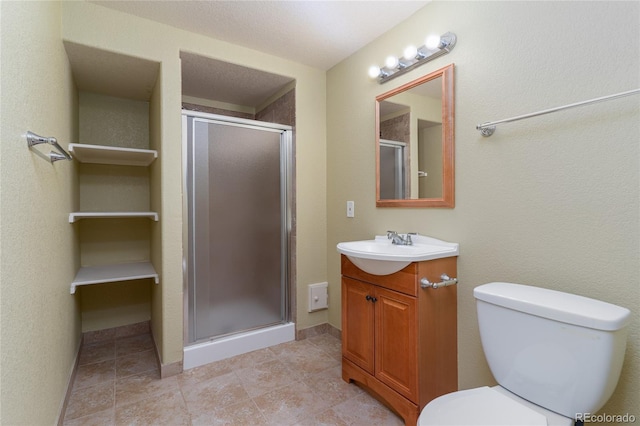 bathroom with a stall shower, vanity, toilet, and baseboards