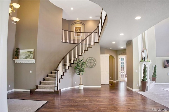 6254 S Riviera Ct, Aurora, CO 80016 - foyer entrance with arched walkways, wood finished floors, stairway, a towering ceiling, and baseboards