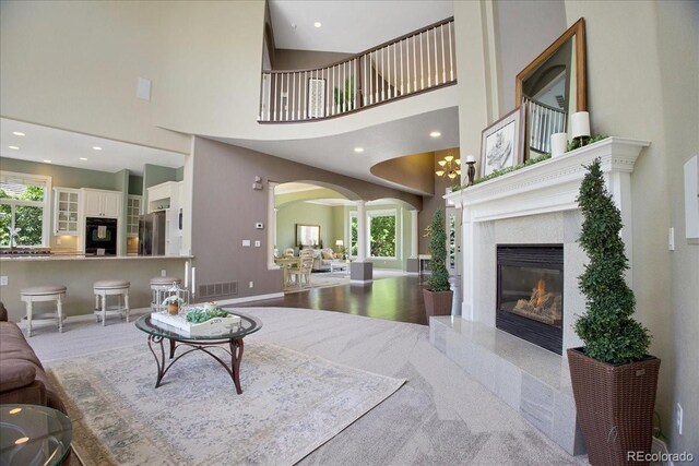 6254 S Riviera Ct, Aurora, CO 80016 - carpeted living area with arched walkways, healthy amount of natural light, a high ceiling, a fireplace, and decorative columns