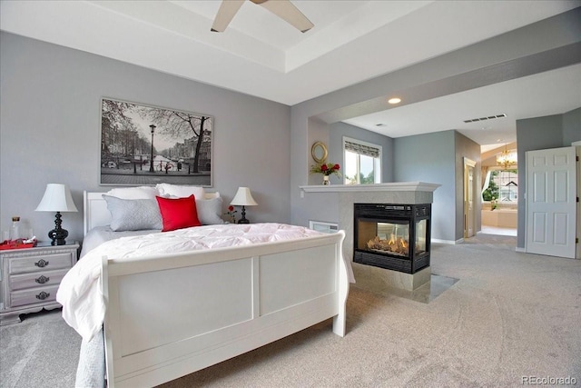 6254 S Riviera Ct, Aurora, CO 80016 - carpeted bedroom with a multi sided fireplace, a raised ceiling, a chandelier, baseboards, and connected bathroom