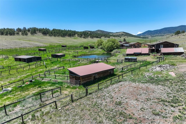 exterior space featuring a rural view, a mountain view, an outdoor structure, and a yard