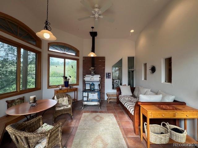 living room with ceiling fan, high vaulted ceiling, and dark tile patterned floors