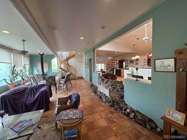 living room with light tile patterned flooring, a wood stove, and ceiling fan