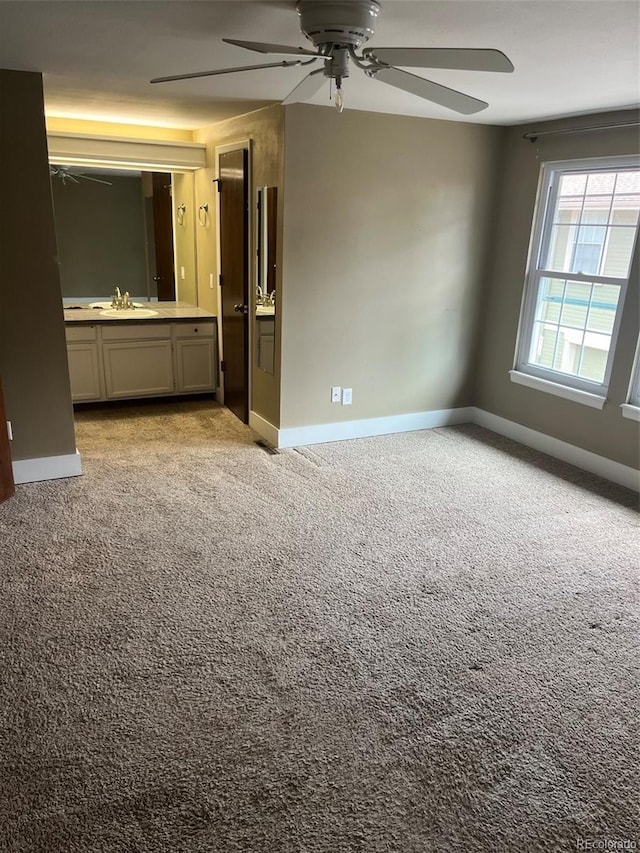 unfurnished bedroom featuring a sink, baseboards, carpet, and a ceiling fan