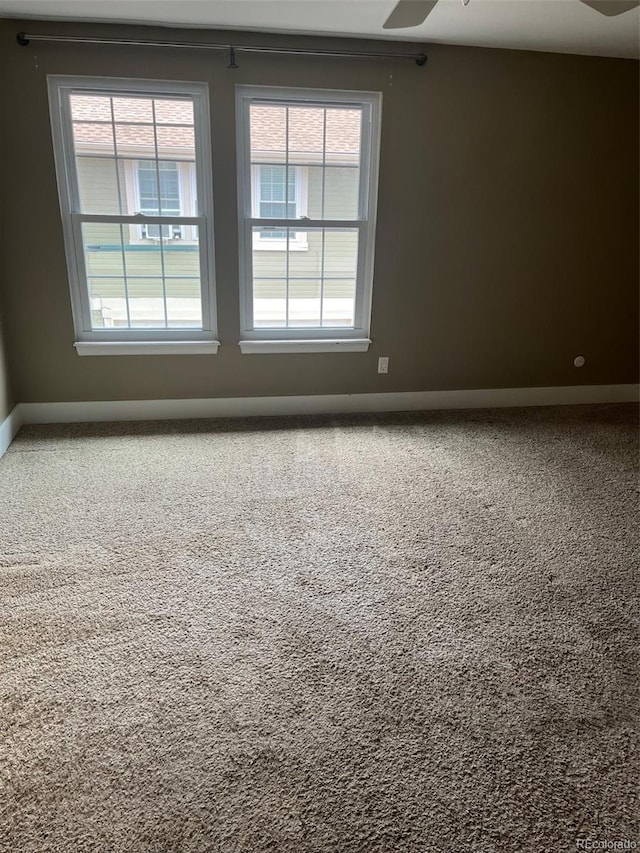 empty room featuring carpet floors, baseboards, plenty of natural light, and ceiling fan