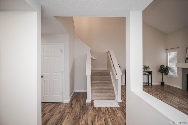 stairs featuring hardwood / wood-style flooring, a tile fireplace, and a textured ceiling