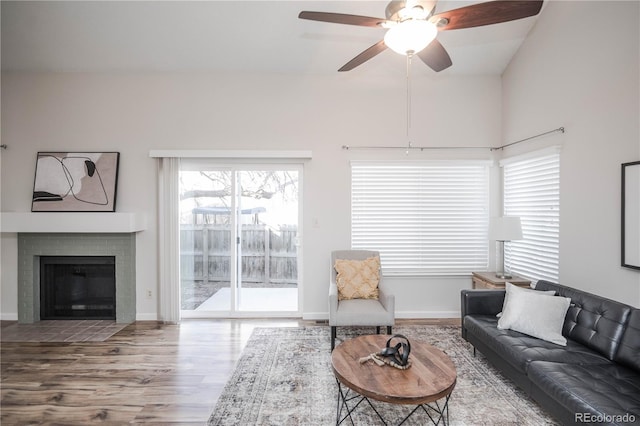 living room featuring a brick fireplace, hardwood / wood-style flooring, and ceiling fan