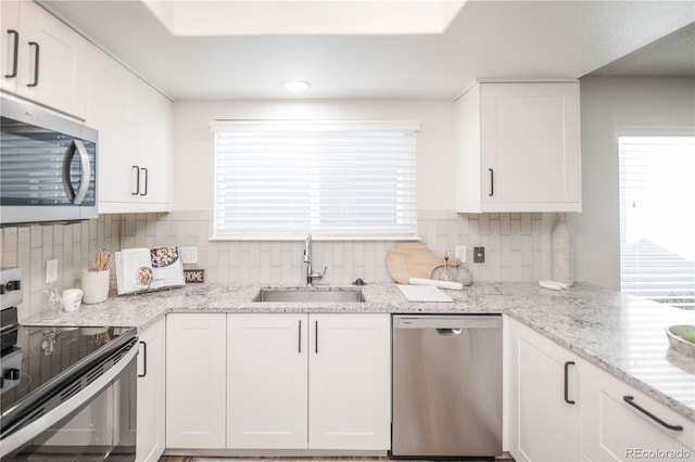 kitchen featuring white cabinetry, sink, light stone counters, and appliances with stainless steel finishes