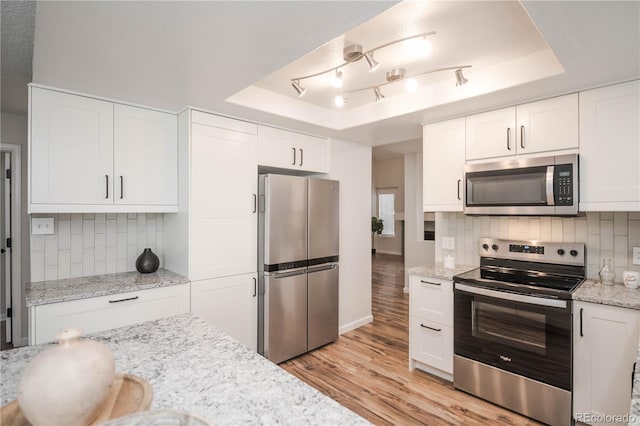 kitchen featuring white cabinetry, appliances with stainless steel finishes, a raised ceiling, and decorative backsplash