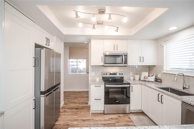 kitchen featuring stainless steel appliances, a raised ceiling, sink, and white cabinets