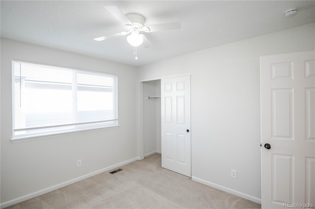 unfurnished bedroom featuring light colored carpet, a closet, and ceiling fan