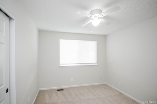 empty room with light carpet, a textured ceiling, and ceiling fan