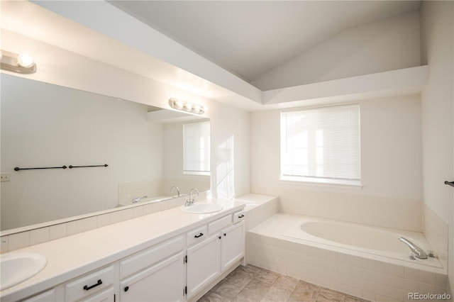 bathroom with vanity, tiled bath, and vaulted ceiling