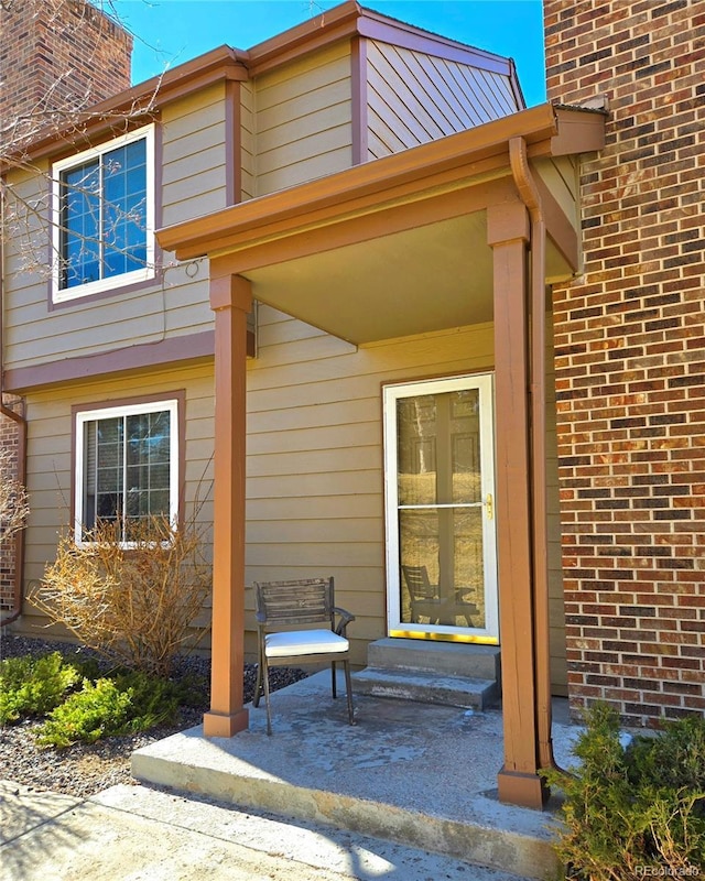 property entrance with a chimney and brick siding