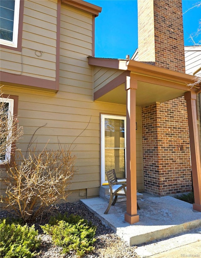 property entrance with brick siding and a chimney