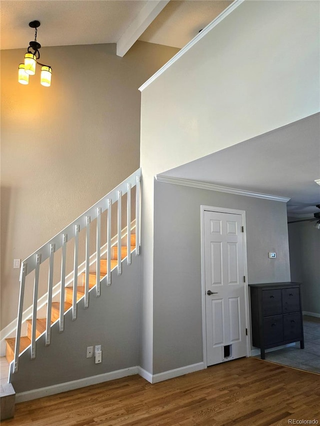 stairway featuring crown molding, lofted ceiling with beams, baseboards, and wood finished floors