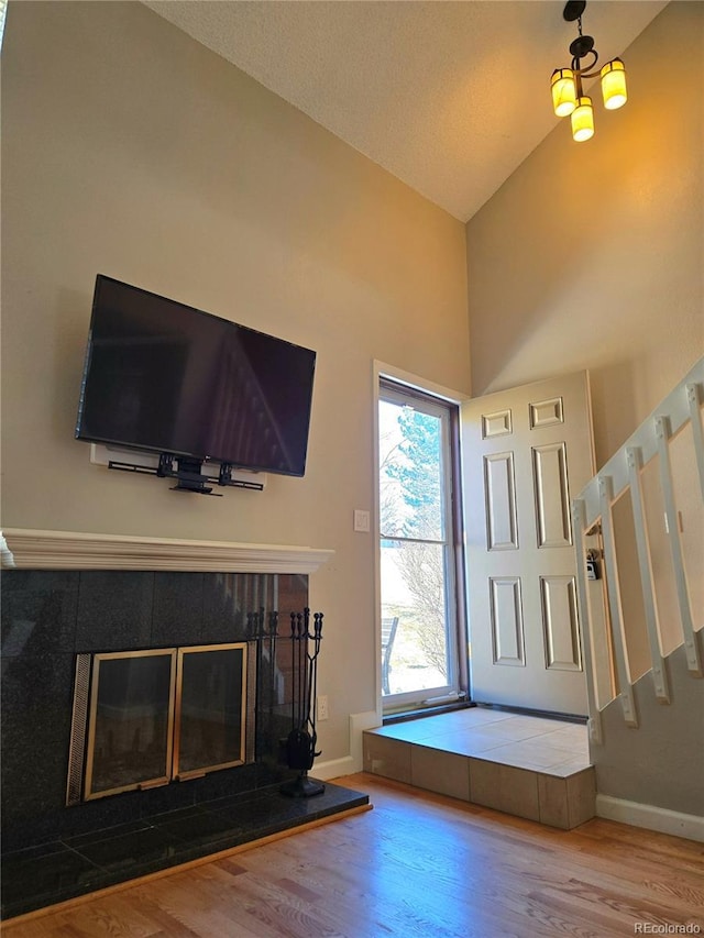 foyer entrance with stairway, baseboards, a tiled fireplace, and wood finished floors
