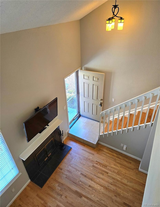 foyer entrance with stairs, high vaulted ceiling, wood finished floors, and baseboards