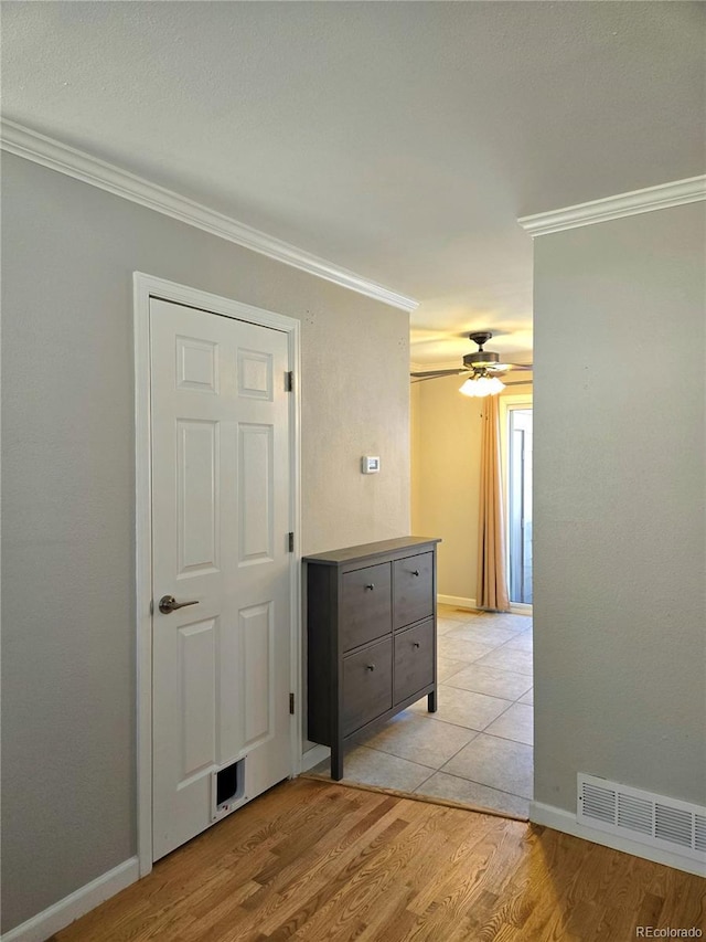interior space with light wood finished floors, baseboards, visible vents, and crown molding