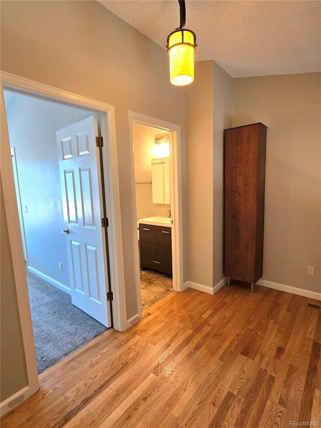 unfurnished bedroom featuring visible vents, light wood-style flooring, baseboards, and ensuite bathroom