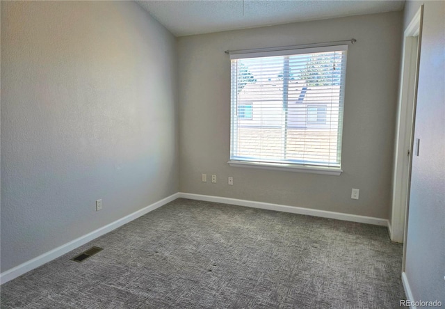 empty room featuring carpet floors, baseboards, and visible vents