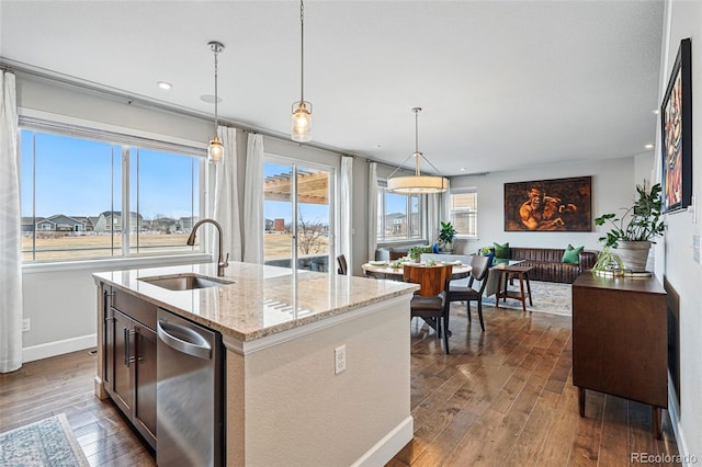 kitchen with dark wood-style floors, a sink, decorative light fixtures, and light stone countertops