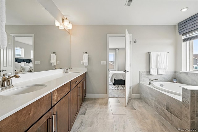 ensuite bathroom featuring ensuite bath, a sink, and a healthy amount of sunlight