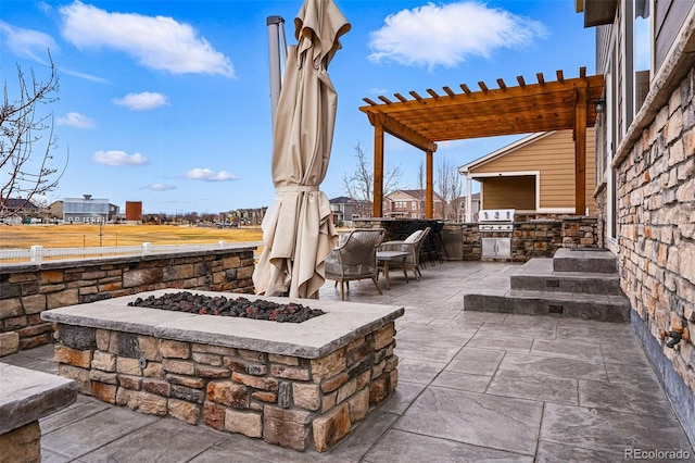 view of patio with a grill, a fire pit, an outdoor kitchen, and a pergola