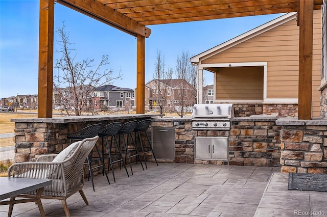 view of patio with a grill, an outdoor kitchen, a pergola, and a residential view