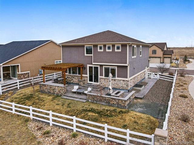 back of house with stone siding, a patio, a garage, fence private yard, and a pergola