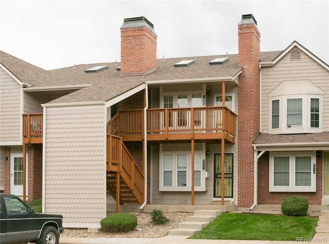 rear view of property with a shingled roof, stairway, and a chimney