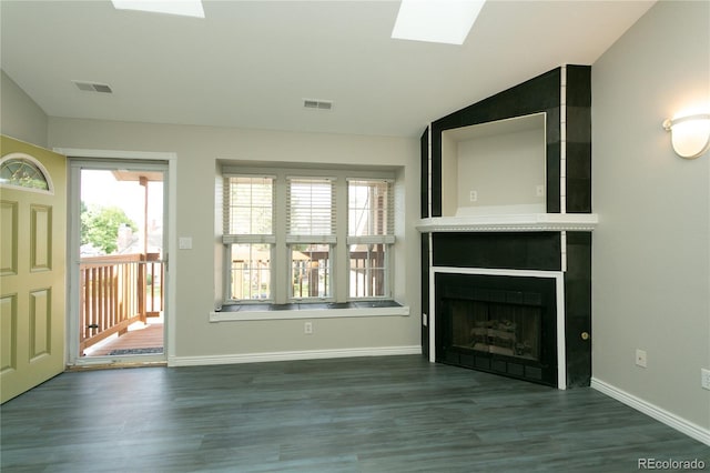 unfurnished living room with vaulted ceiling with skylight, a fireplace, wood finished floors, and baseboards