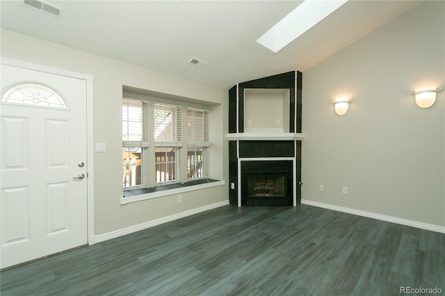 unfurnished living room with a large fireplace, wood finished floors, visible vents, baseboards, and lofted ceiling with skylight