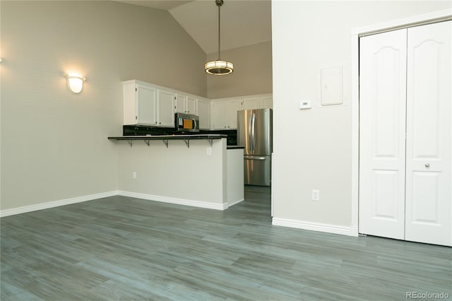 kitchen featuring white cabinets, dark countertops, a peninsula, stainless steel appliances, and pendant lighting